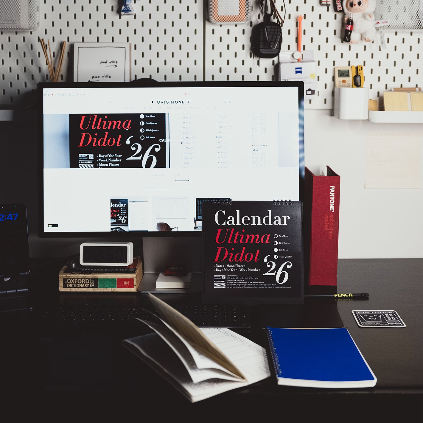 Desk setup with computer monitor displaying a calendar, books, and stationery items.